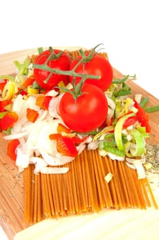 Ingredients for spaghetti on wooden cutting board over white background