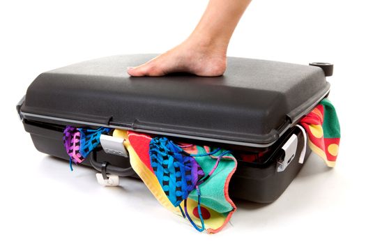 Foot on stuffed suitcase over white background