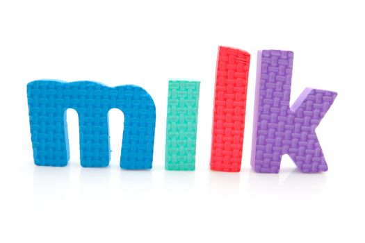 Word milk in colorful foam letters over white background