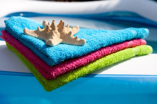 summer gear; colorful towel, life buoy and starfish by the swimpool