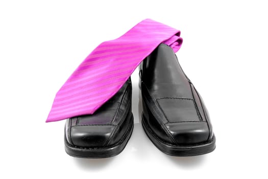 Pair of black male business shoes and pink tie isolated on white background