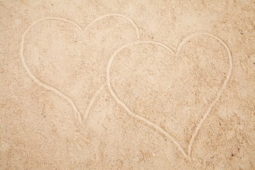 two hearts drawn in sand in closeup
