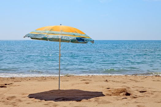 Lonely umbrella on the beach near the ocean on sunny day
