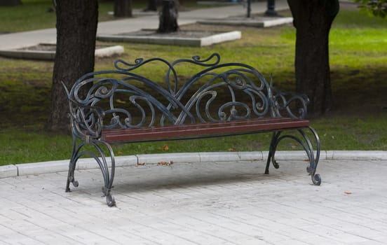 Metal forged bench in summer park with abstraction curles