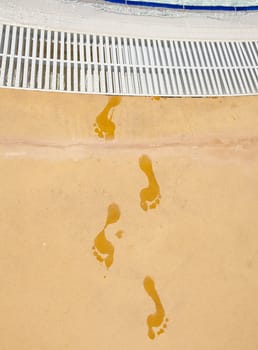 trail of wet footprints near the swimming pool
