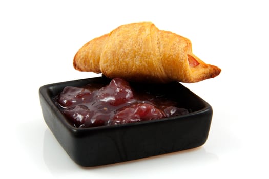 fresh baked croissant and bowl with marmalade over white background