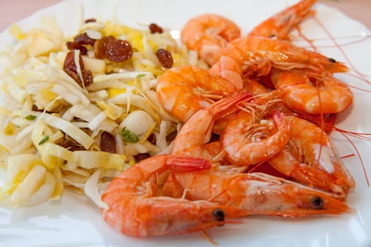 plate with dinner, shrimp and chicory in closeup