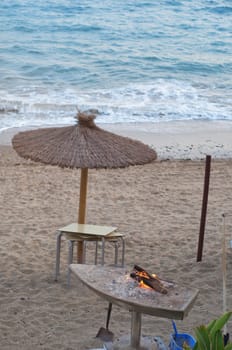 Umbrella on the beach and fireplace with fire