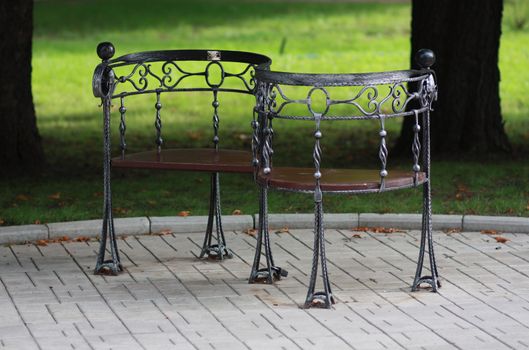 Metal forged bench in summer park with S-form