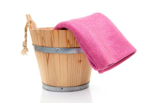 wooden bucket for spa or sauna with pink towel over white background