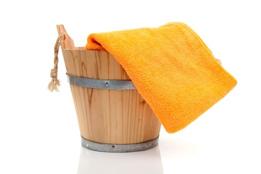 wooden bucket for spa or sauna with orange towel over white background