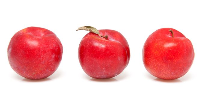 three red plums in a row over white background