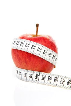healthy diet; red apple with measure tape over white background