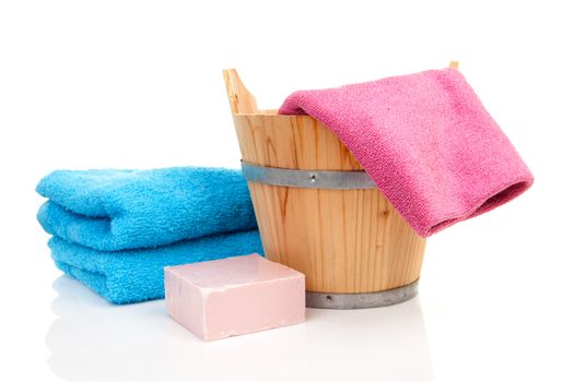 wooden bucket for spa or sauna with colorful towels and soap over white background