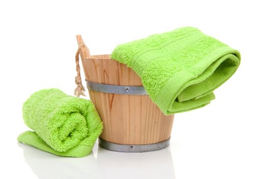 wooden bucket for spa or sauna with green towels over white background