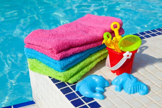 colorful towels and plastic toys near the swim pool