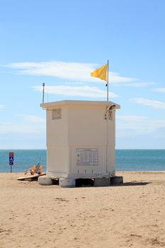 lifeguard hut at the beach with yellow flag on sunny day