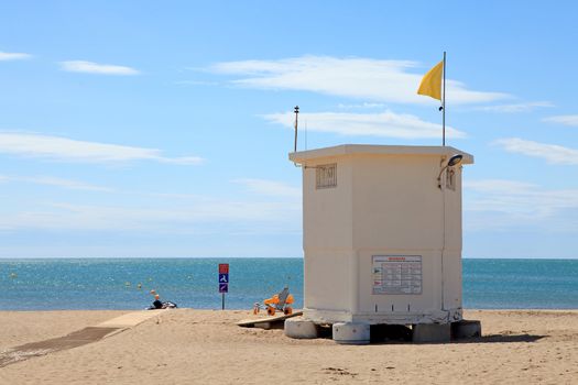 lifeguard hut at the beach with yellow flag on sunny day