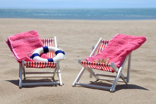 chairs on the beach with towels and life buoy