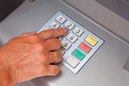 Hand is entering personal identification number on ATM dial panel
