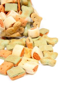 Pile of dog cookies falling out of bag over white background