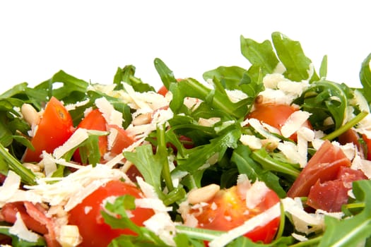 Fresh rucola lettuce with tomatoes, pine kernels and Parmesan cheese over white background