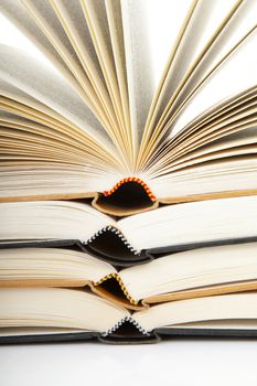 pile of open books in closeup over white background

