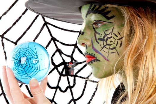 Portrait of green Halloween witch girl in closeup holding big blue marble