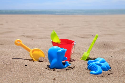 colorful plastic beach toys in the sand near the ocean