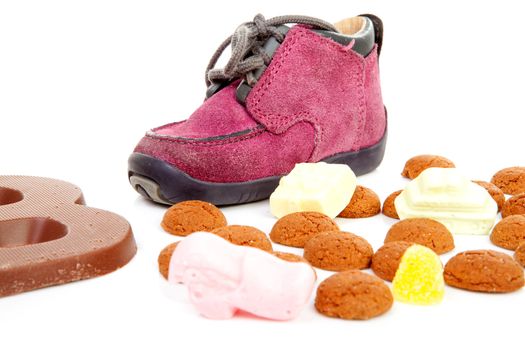 purple little children's shoe with chocolate letter and pepernoten ( ginger nuts), traditional for Sinterklaas in the Netherlands over white background