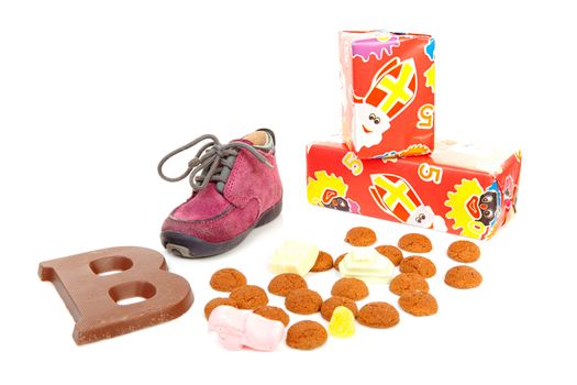 purple little children's shoe with chocolate letter, presents and pepernoten ( ginger nuts), traditional for Sinterklaas in the Netherlands over white background