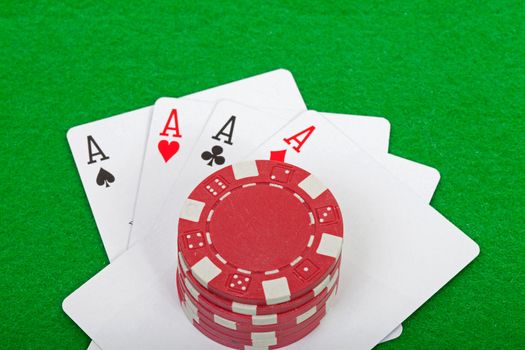 winning poker hand of four aces playing cards and chips on green background