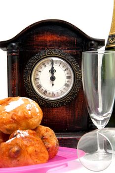 Dutch donut also known as oliebollen, traditional New Year's eve food and clock on midnight isolated on white background