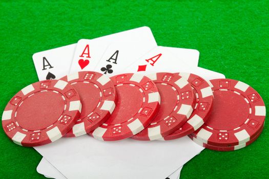 winning poker hand of four aces playing cards and chips on green background