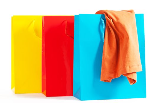 three colorful shopping bags with a orange shirt on white background