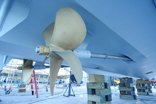 close up of boat propeller that is up on blocks in boat yard