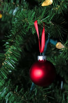 matte red christmas ornament hanging on tree with lights