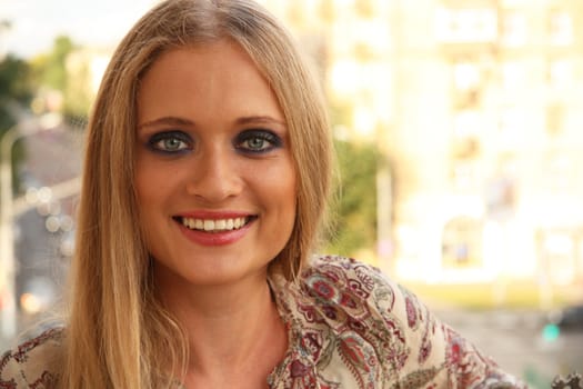 Outdoor portrait of a beautiful blonde Caucasian young woman with smoky eyes make up