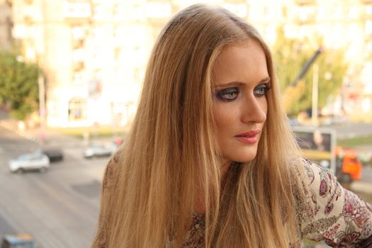 Outdoor portrait of a beautiful sad blonde Caucasian young woman with smoky eyes make up