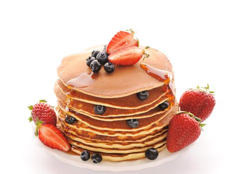 Delicious freshly prepared pancakes with strawberry and blueberries isolated on white