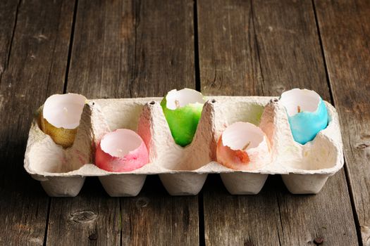 Colored easter eggs candles on wooden table