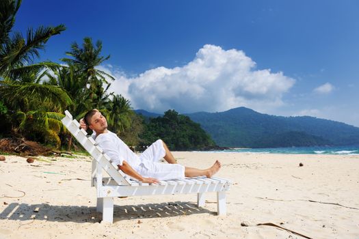 Man in white relaxing on a tropical beach