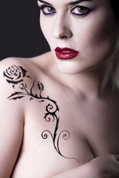 Sensual beautiful nude brunette girl with tribal tattoo rose
