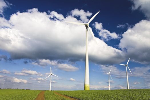 Windmills against a blue sky and clouds, alternative energy source, in horizontal frame