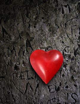 Photo of a metal heart on a damaged stone wall.

