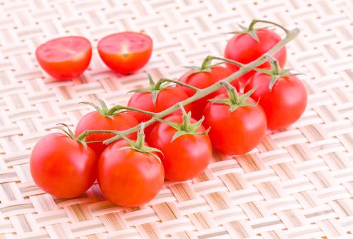 Bunch of fresh small cocktail tomatoes on a straw braided mat