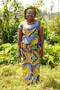 Candid and complete body shot of a beautiful mature black African woman wearing tradition clothes, in bold graphics and colors, called boubou, outdoors.