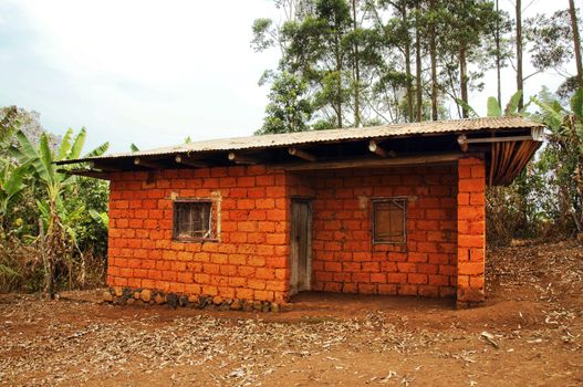 Typical red earth or soil brick with tin roof house for the workers and the like, in Africa. 