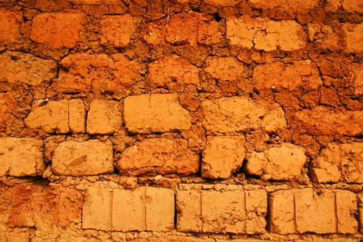 Wall of a house in red clay, earth or soil bricks, great texture background, poverty, developing or tropical country concept.