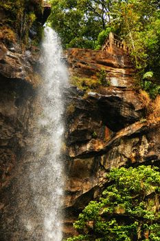 Beautiful sacred waterfall with colonial observation deck deep into the thick and lush african tropical forest, great nature background.